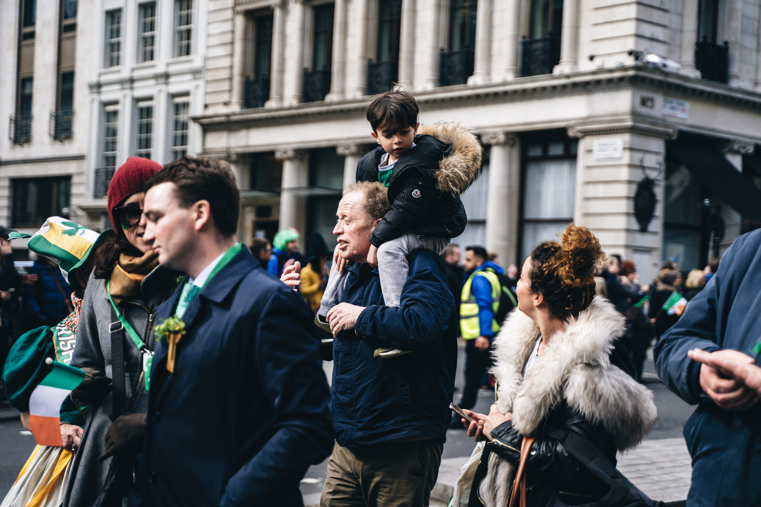 Man with a kid on shoulders at St. Patricks Day Parade