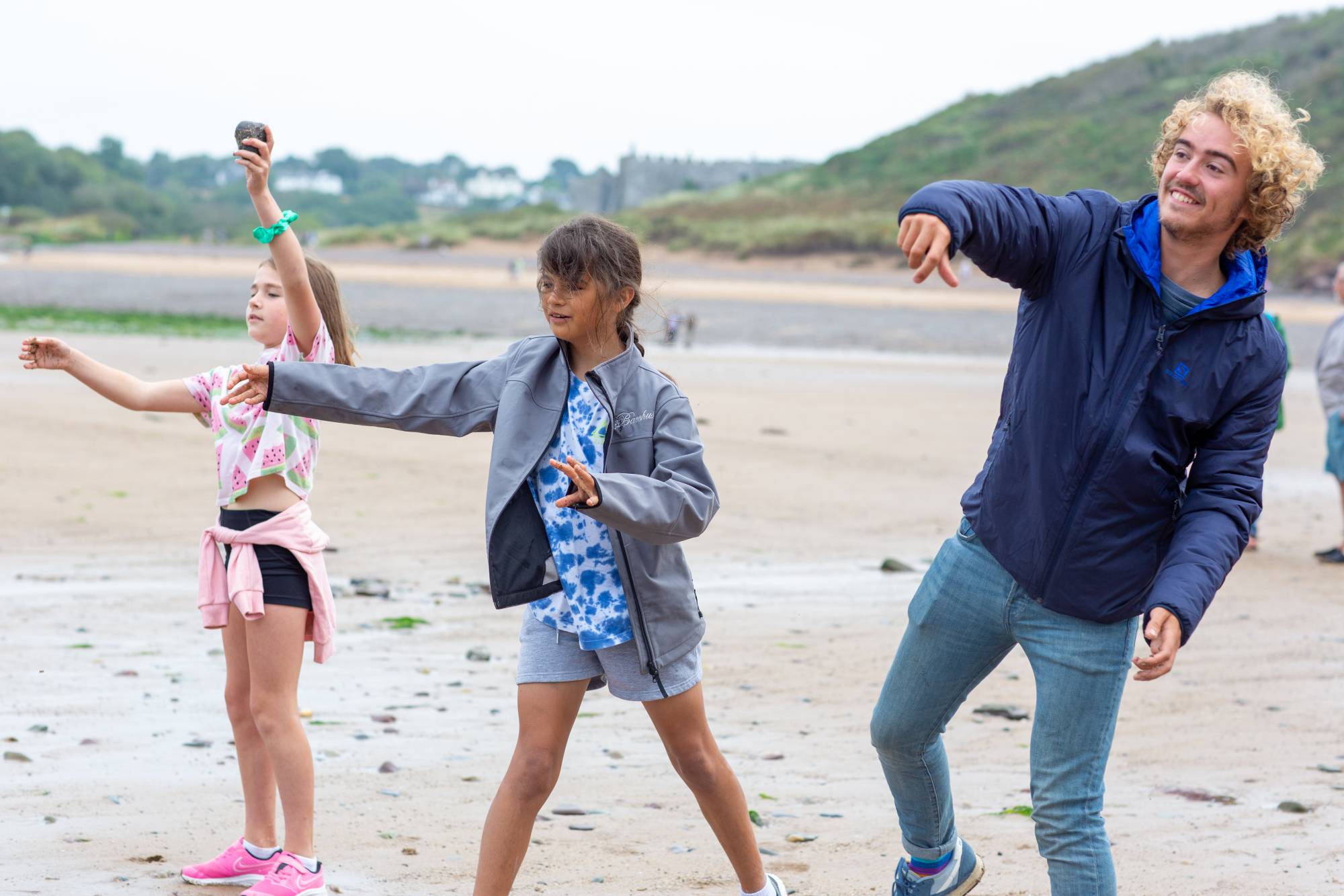 Three siblings skimming rocks on the beach