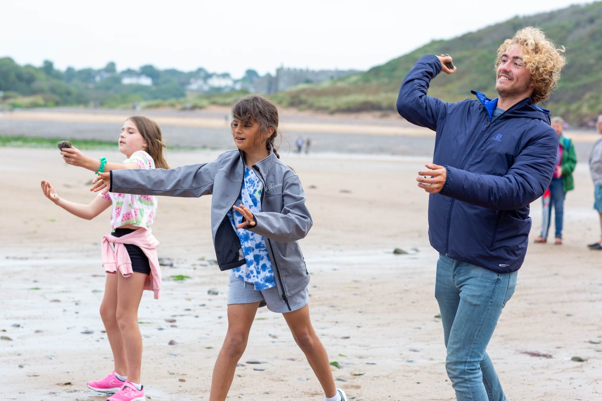 A brother and two sisters skimming rocks on the beach